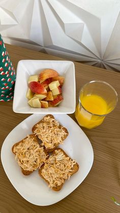 two white plates filled with food next to a glass of orange juice and an apple