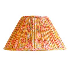 a lamp shade with an orange and pink flower pattern on the bottom, sitting on a white background