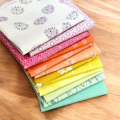 a stack of different colored fabrics sitting on top of a wooden table