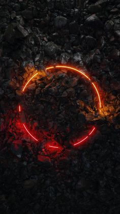 a red neon circle sitting on top of a pile of rocks