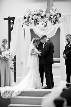 a bride and groom standing at the alter during their wedding ceremony in black and white