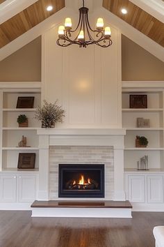 a living room filled with furniture and a fire place under a chandelier hanging from the ceiling