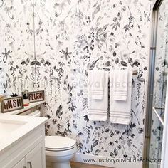 a white toilet sitting next to a sink under a bathroom mirror with two towels hanging on it