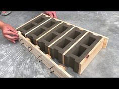 a person is placing cinder blocks into a wooden box on the ground with their hands