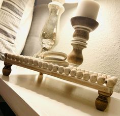 a candle is sitting on top of a white table with beads and candlesticks