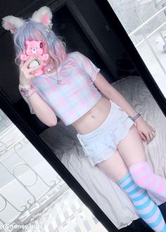 a woman with pastel hair is laying on a bed and holding a teddy bear