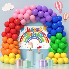 a birthday party with balloons, cake and gifts in front of a rainbow arch on the wall