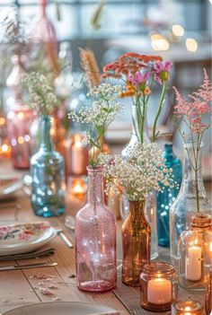 there are many different vases with flowers in them on the dining room table set for dinner