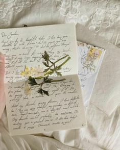 an old letter with flowers on it is being held by someone's hand while laying in bed