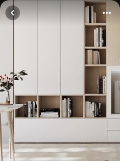 a living room filled with furniture and bookshelves next to a vase full of flowers