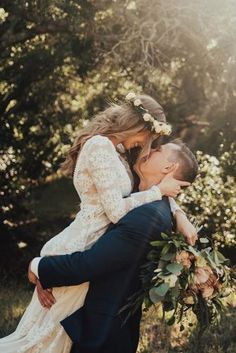 a bride and groom kissing in front of trees with sunlight coming through the leaves on them