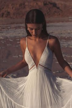 a woman wearing a white dress standing in the desert