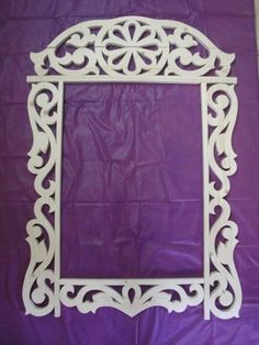 an ornate white frame sitting on top of a purple sheet