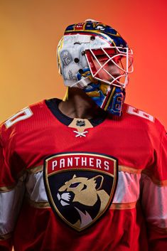 a hockey goalie wearing a red jersey and mask