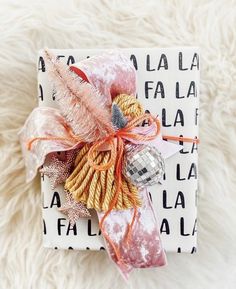 a wrapped present on top of a white furnishing covered box with an orange ribbon