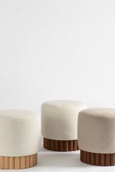 three white stools with wooden bases on a white surface, one in the foreground and another in the background