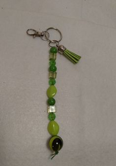 a green and black beaded keychain with tassels hanging from it