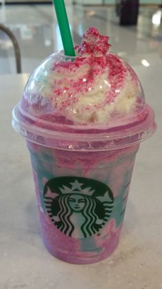 a pink drink with sprinkles and a green straw in a plastic cup