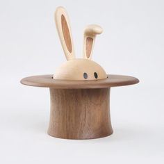 a wooden toy rabbit sitting on top of a hat