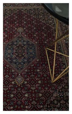 a red rug with an intricate design on the bottom, and a black table in front