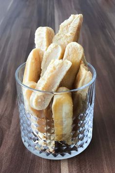 a glass bowl filled with sliced bananas on top of a wooden table next to a knife