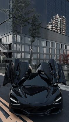 a black sports car parked in front of a tall building