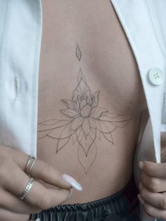 a woman's stomach with a flower tattoo on her chest and one hand holding the other