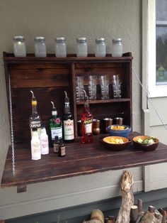 an outdoor bar with liquor bottles and bowls on the shelf, along with other drinks