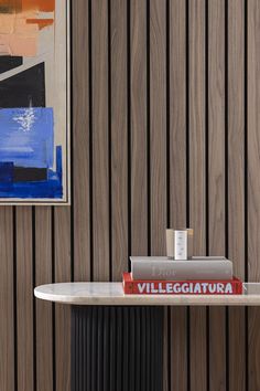 two books are sitting on a table in front of a wall with wood paneling