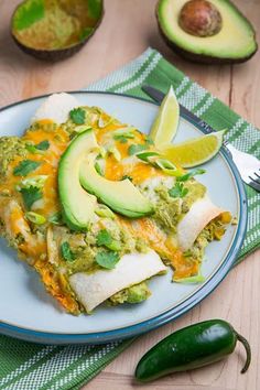 an enchilada with avocado, cheese and cilantro on a plate