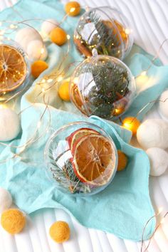 oranges and other fruit are in glass bowls on a blue towel with pom - poms around them