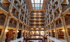 the inside of a large library with lots of bookshelves and tables in it