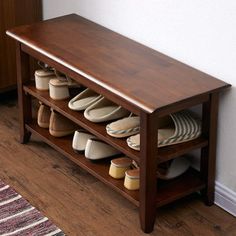 a wooden bench with several pairs of shoes on it next to a rug and door