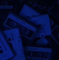 a pile of cassette tapes sitting next to each other in the dark blue light,