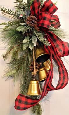 a christmas wreath with bells hanging from it's side and pine cones on top