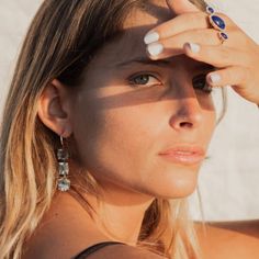 a woman is holding her hand up to her face and looking off into the distance