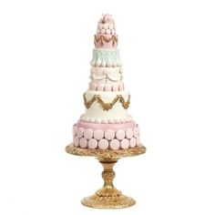 a three tiered cake sitting on top of a gold plate with pink and white frosting