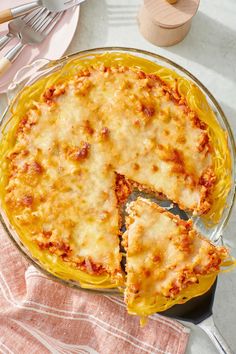 a cheesy casserole dish with one slice cut out and fork next to it