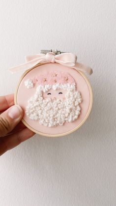 a hand holding a small embroidered ornament with a sheep on it's face