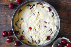 a pan filled with ice cream and cherries on top of a wooden table