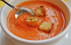 a white bowl filled with tomato soup and croutons