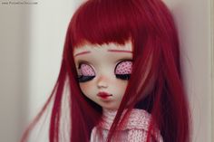 a close up of a doll with red hair and pink eyeliners on her eyes