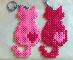 two pink and one red perler bead keychains on a white surface