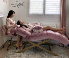 two women laying on a pink couch in a room with white walls and window curtains