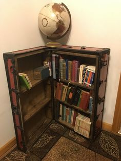 an old bookcase with a globe on top and books in the bottom, sitting next to a wall