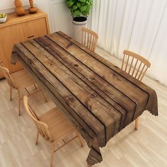 a wooden table with chairs around it and a potted plant in the corner behind it