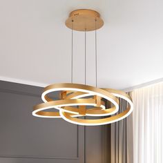 a modern chandelier hanging from the ceiling in a room with grey walls and curtains