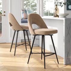 two stools sitting on top of a hard wood floor next to a kitchen counter