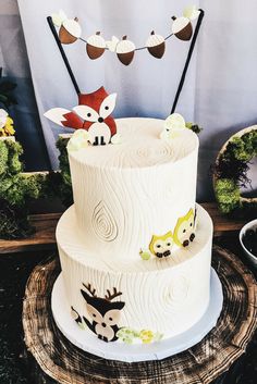 a three tiered cake with woodland animals on it and the words woodland themed party decor