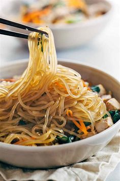 someone is eating noodles with chopsticks in a bowl